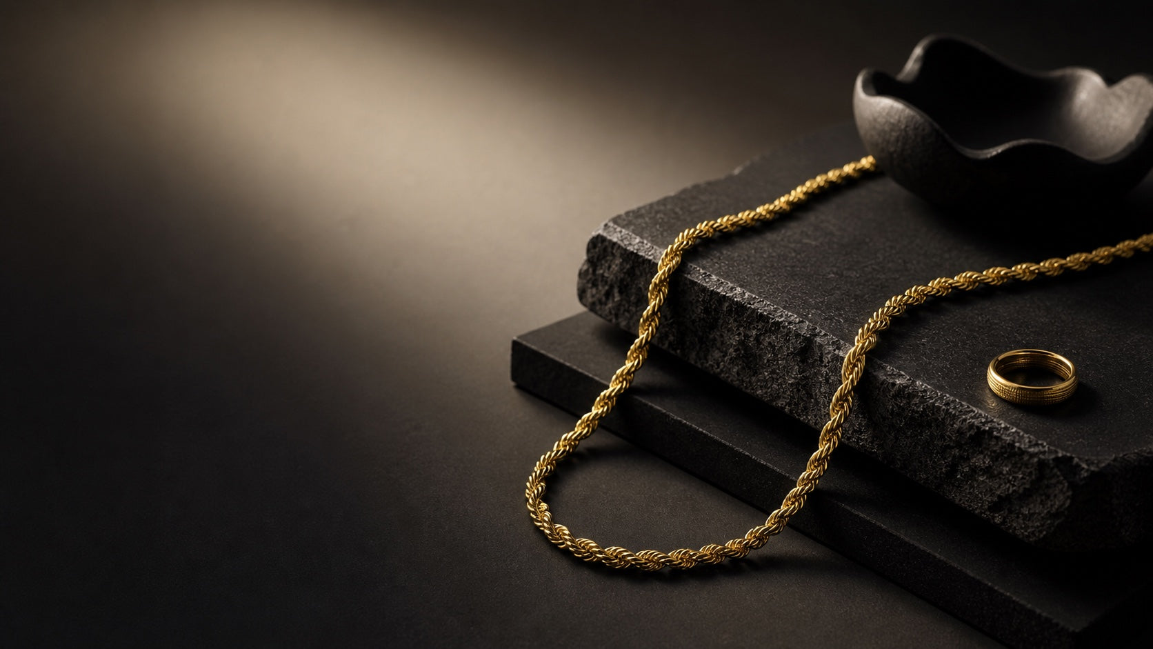 Gold rope chain and ring styled on charcoal stone