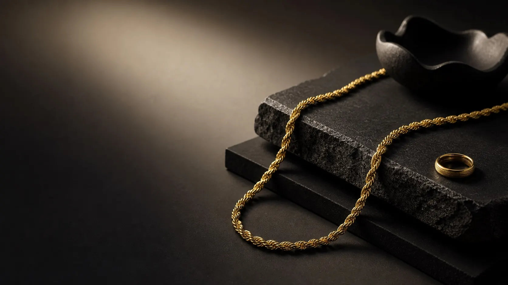 Gold rope chain and ring styled on charcoal stone